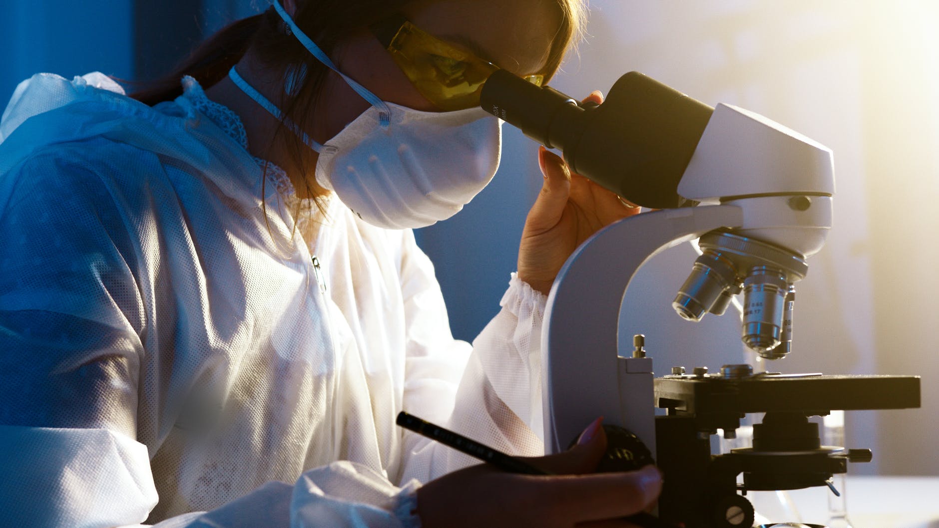 a woman looking at the camera while holding the eyepiece of the microscope
